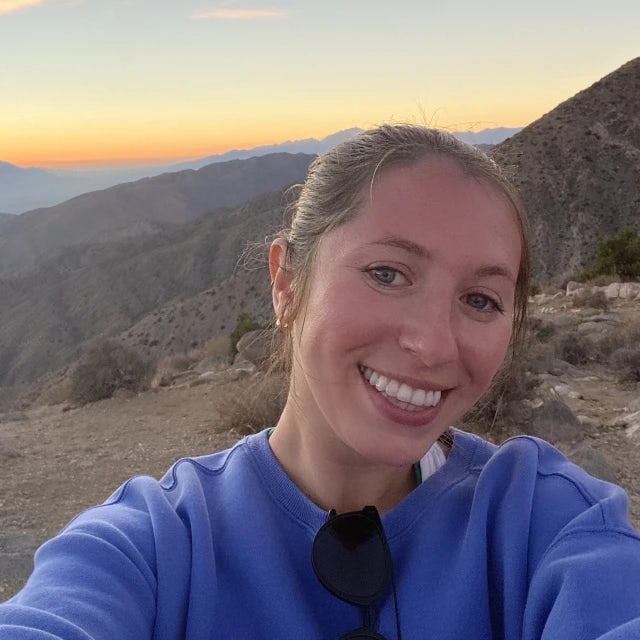 Travel Advisor Meryl Honig with a blue sweatshirt at sunset in the mountains.