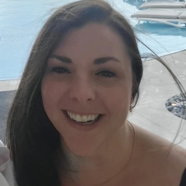 Travel advisor Lauren Taylor with dark brown hair smiling in front of a pool