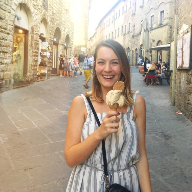 Travel Advisor Lindsay Maynard holds an ice cream cone on an ancient city street wearing a white and gray striped dress