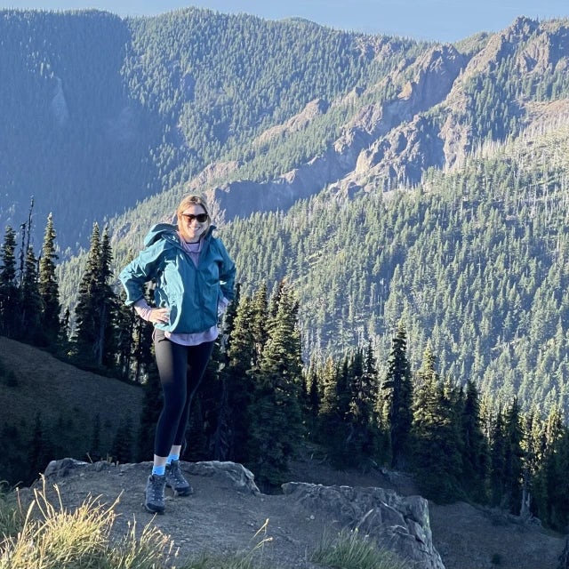 Travel advisor Rachel Webb in a blue puffer jacket standing on a mountain trail