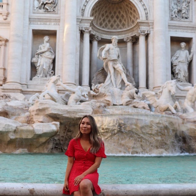 Fora travel agent Mary Xiao wearing red dress sitting at fountain in Italy