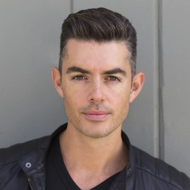 travel advisor Jason Leon, with close-cropped gelled hair, wearing a black tee and a black leather jacket