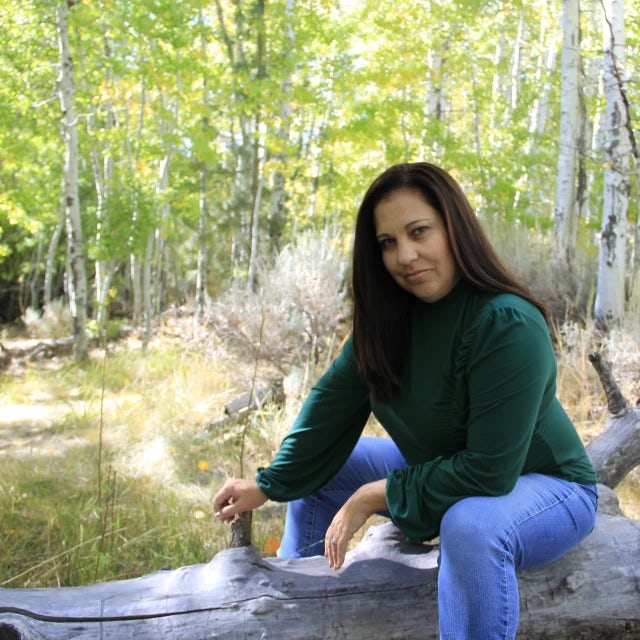 Travel advisor Alena Grace Saporsky in a green shirt in the forest.