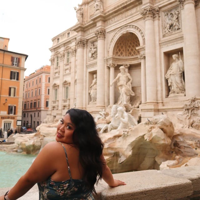 travel advisor Cindy Jimenez in a blue sundress in front of an ancient fountain