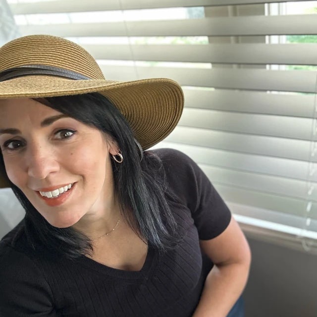 travel advisor Jennifer DiDonna in a tan hat and black shirt in front of window blinds
