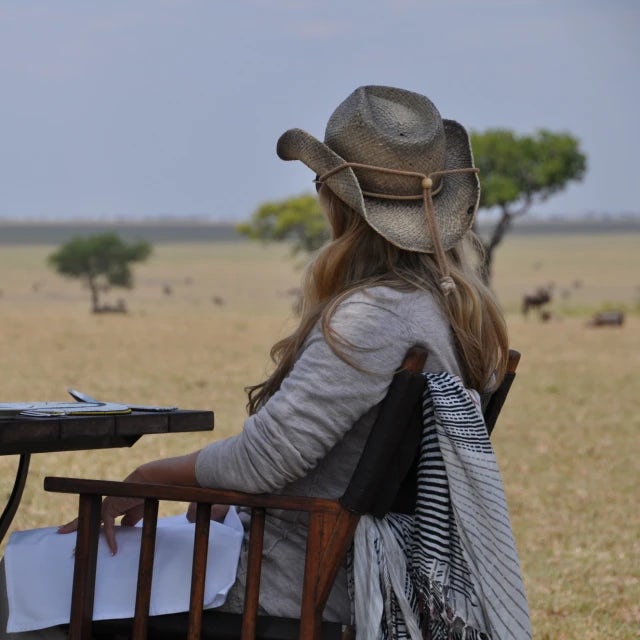 Travel advisor Jennifer Seelicke in a cowboy hat sitting at a table overlooking a meadow