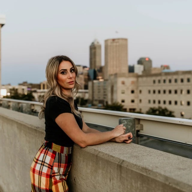 travel advisor Taylor Nefouse in a plaid skirt and black shirt on a rooftop