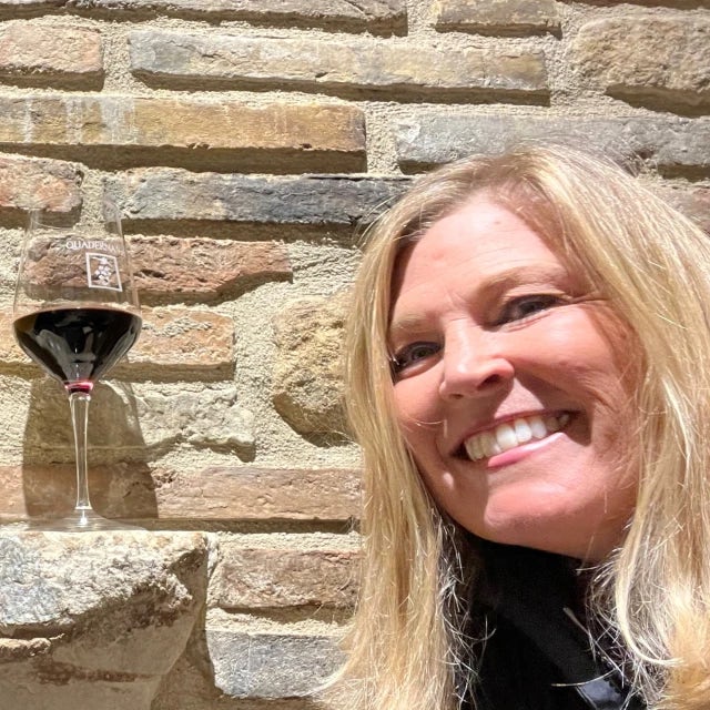 Travel advisor Kelly Mordini with blonde hair smiling in front of a brick wall
