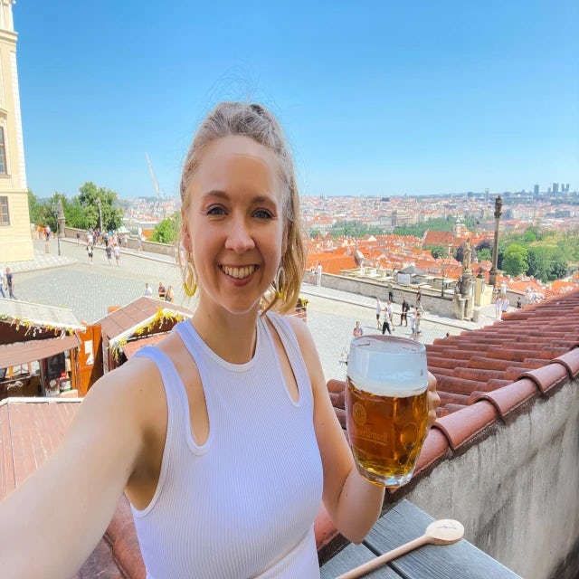 Travel advisor Kacie Yearout holds a pint of beer in one hand and holds her arm out for a selfie on a rooftop
