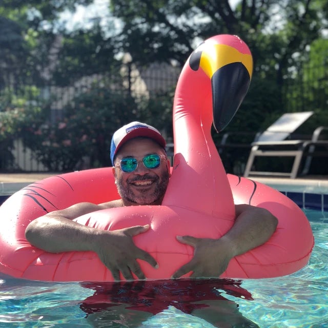 Travel Advisor Michael Sanchez holding a pink flamingo floatie in a pool.