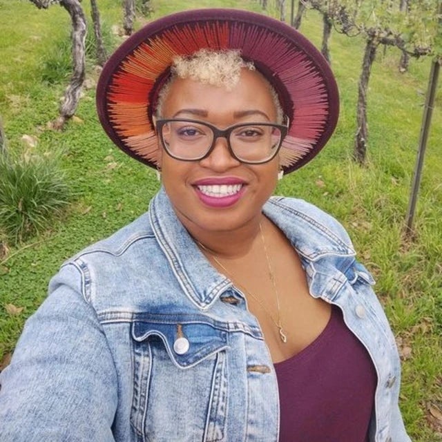 Travel advisor Carissa Rhule wears a pink and orange sunhat in a wine vineyard