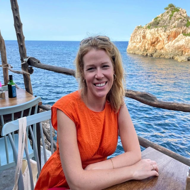 Travel Advisor Jessica Rodgers wears an orange dress at a restaurant on the water