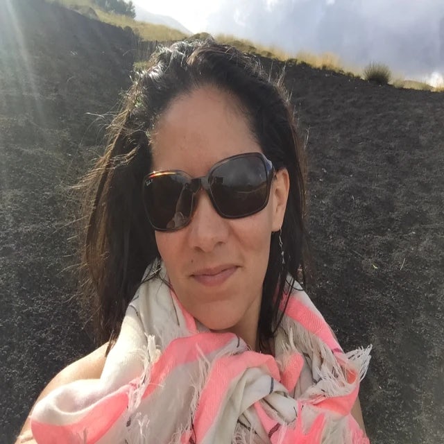 Travel Advisor Lina Santiago Roda in a pink-and-white scarf and sunglasses smiles 
