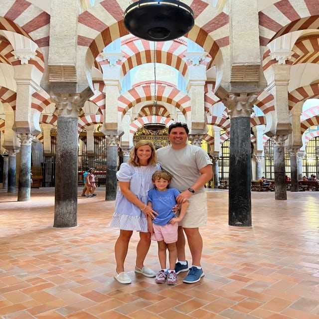 Travel Advisor Gray Grandy with her husband and son and brown/white arches behind.