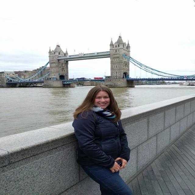 Travel Advisor Hilary Gwaltney in a blue jacket standing in front of the Tower Bridge in London.
