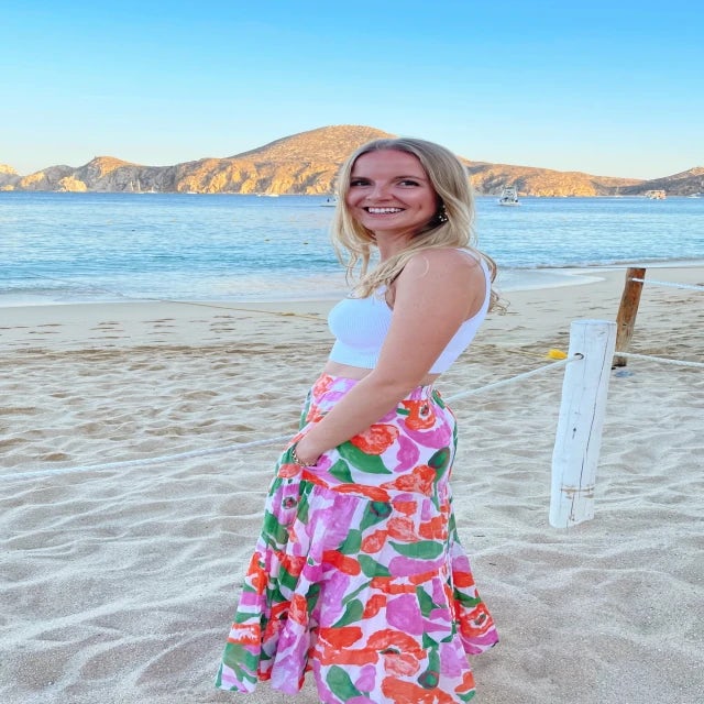 Travel Advisor Isabelle Paradis wears a colorful pink, orange and green maxi skirt on a sandy island beach