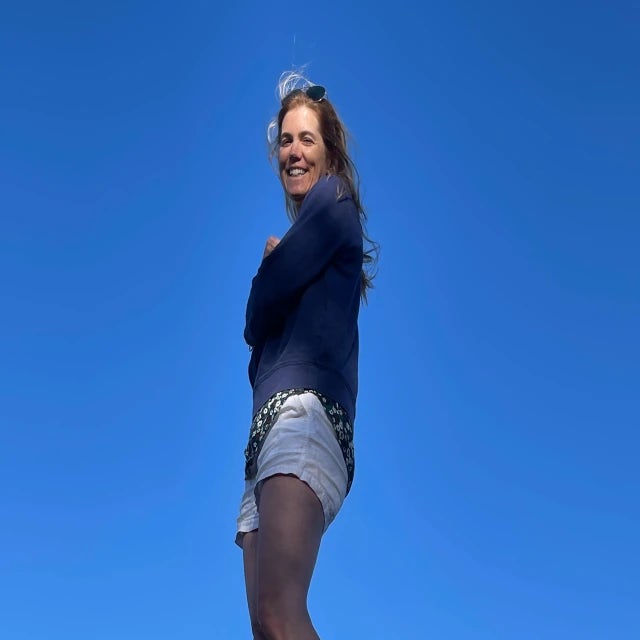 woman wearing black shirt and jean shorts with blue skies
