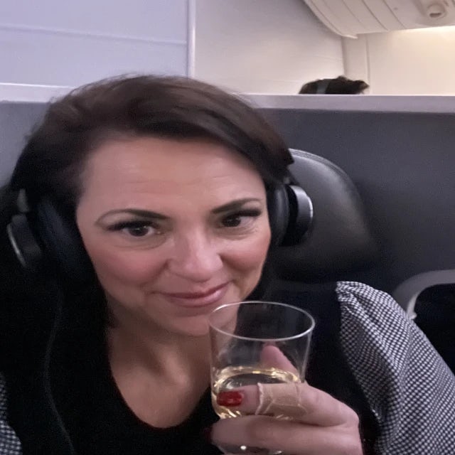 Travel Advisor Jeni Stivale on a plane with a glass of champagne.