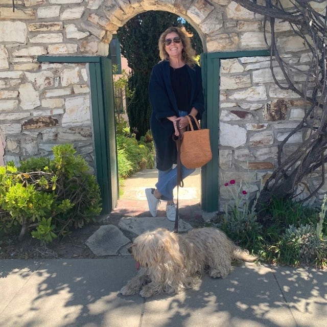 Travel Advisor Kim Hardcastle standing in a green and stone archway with her tan dog.