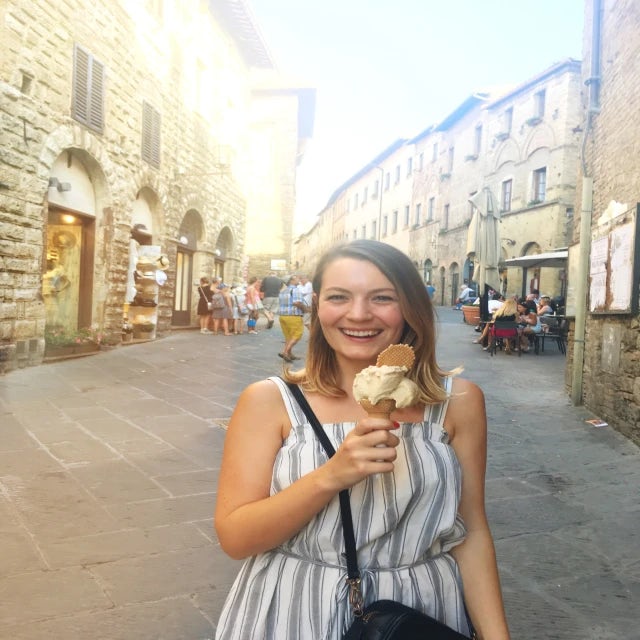 Travel Advisor Lindsay Maynard holds an ice cream cone on an ancient city street wearing a white and gray striped dress