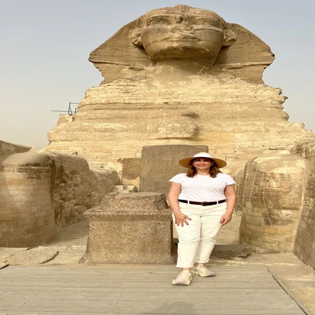 Fora travel agent Gia Crecelius wears white hat and stands in front of historical landmark