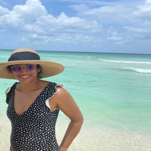 FORA travel agent Kirti Rao wearing wide brimmed hat and black bathing suit on the beach