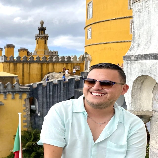 Fora travel agent Miguel Bautista wearing sunglasses with yellow building in background
