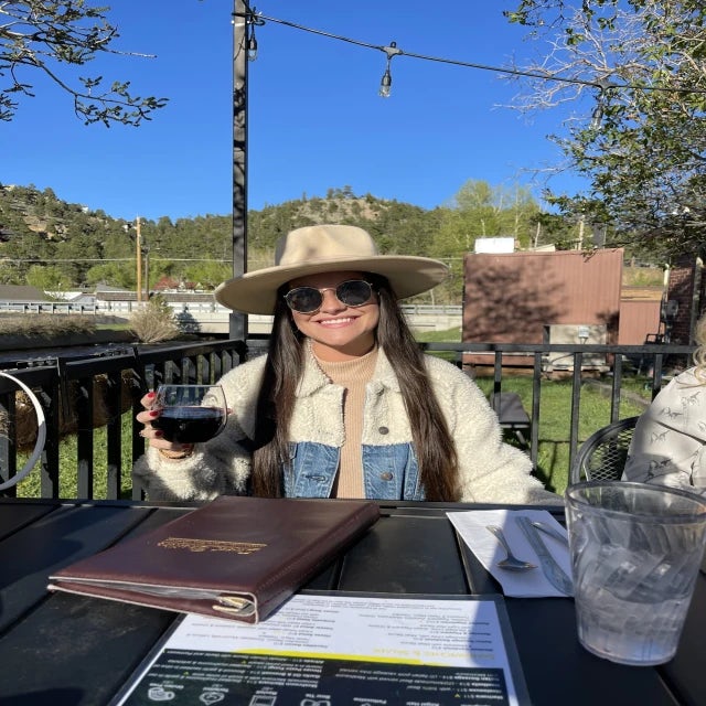 Travel advisor Miranda Powell in a hat and sunglasses holding a glass of red wine