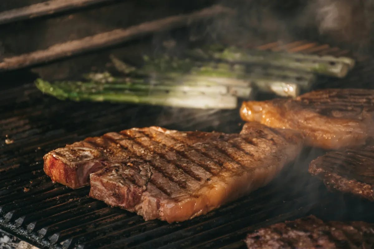 A picture of grilled meat on a charcoal grill.