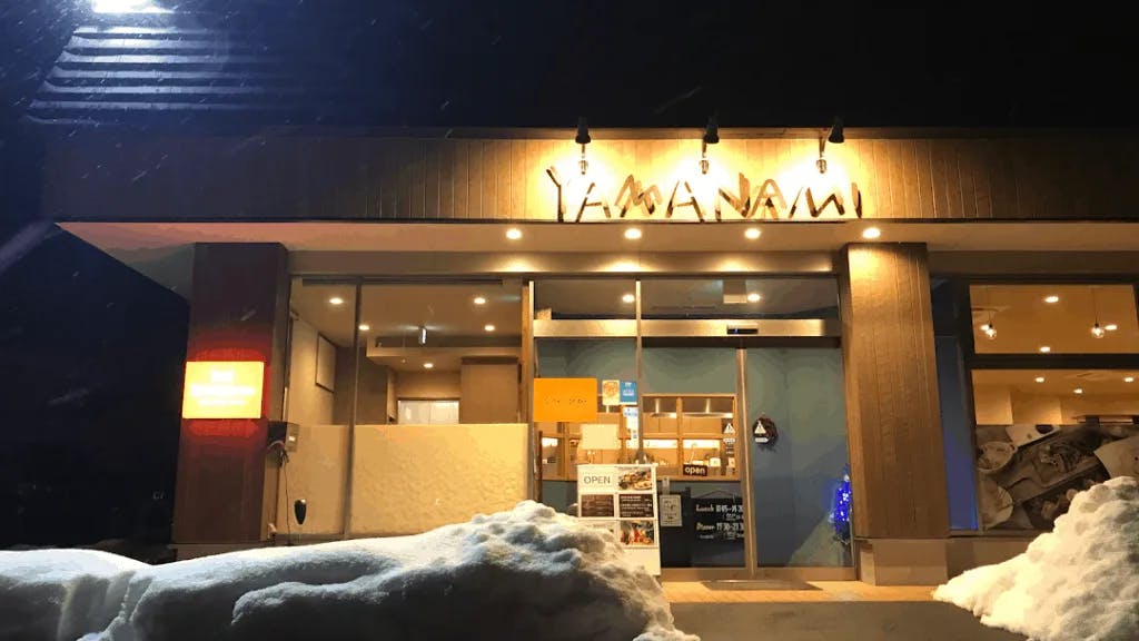 Exterior of a restaurant at night with mounds of snow in front
