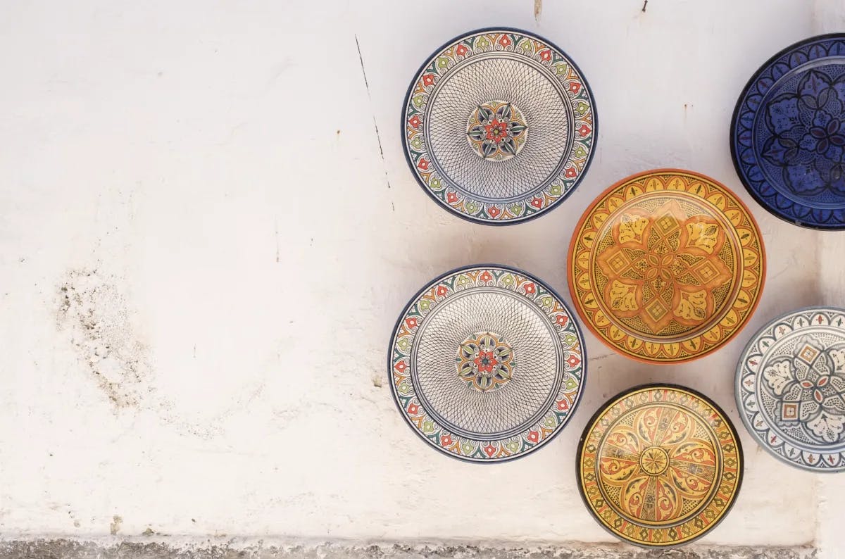 Various decorative plates on a white stone wall.