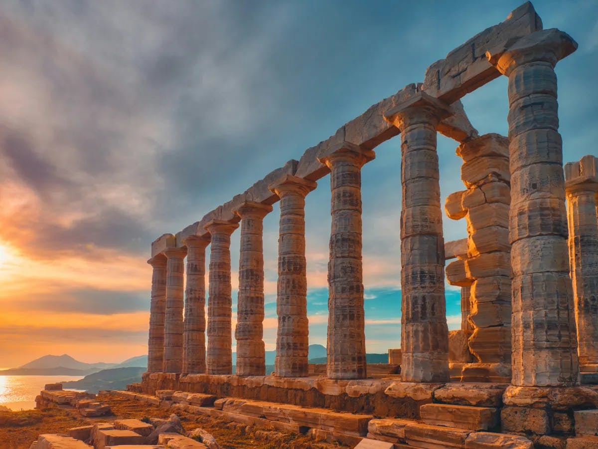 A picture of the ancient building with pillars during sunset.