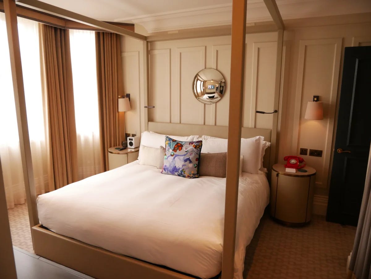 A double bed, with a fluffy pillows in a hotel room, decorated with beige tones.