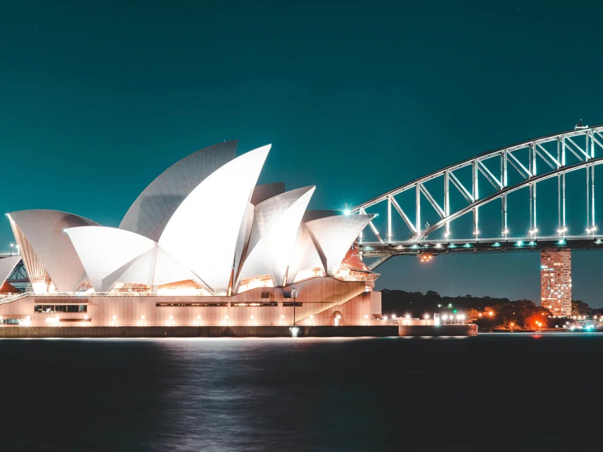 The image features the iconic Sydney Opera House and Harbour Bridge at night, a testament to architectural grandeur under the stars.