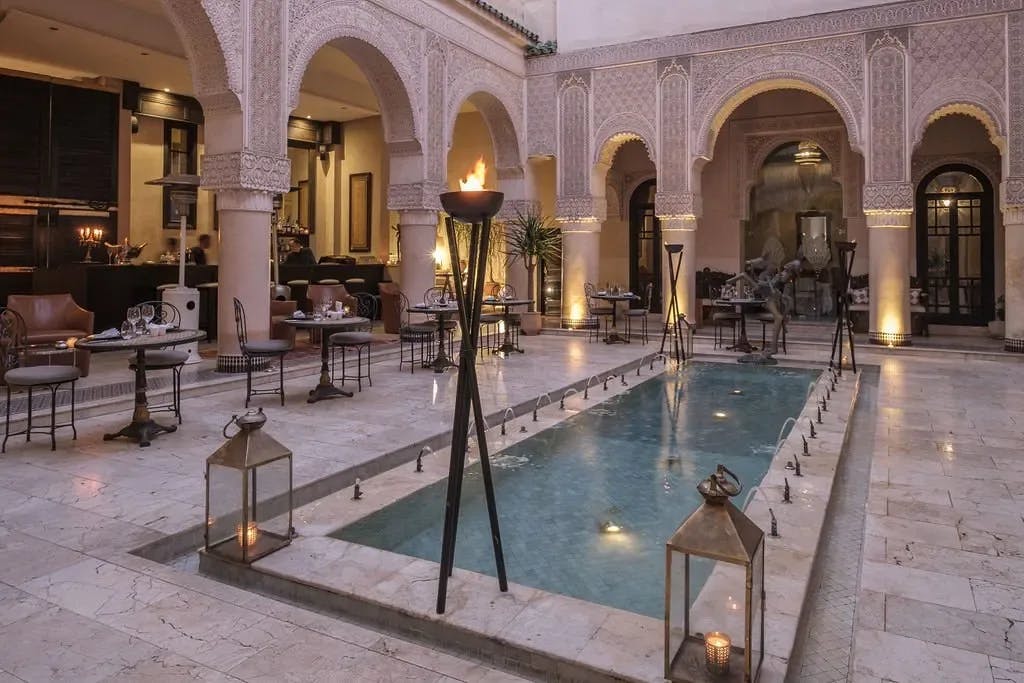 A small rectangular reflection pool in a chic courtyard with curved arches. 