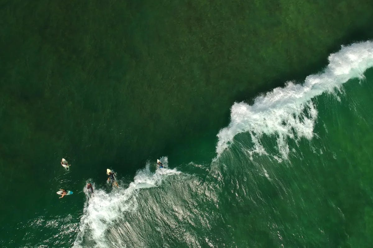 An aerial view of the ocean with surfers surfing during the daytime.