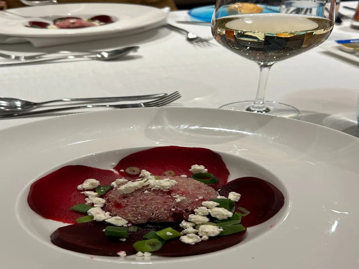 A picture of a food item served on a white plate with a wine glass at a restaurant.
