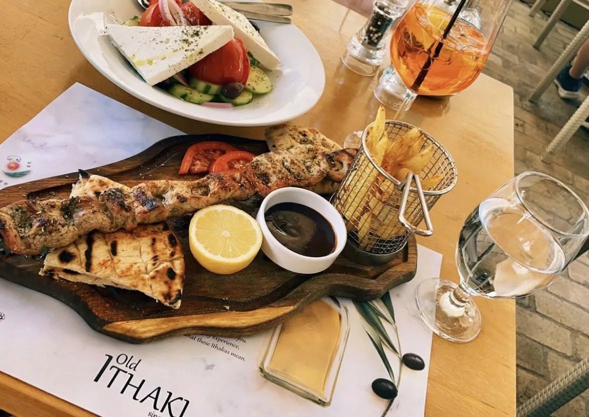 A plate of Greek food and drinks on top of a table. 