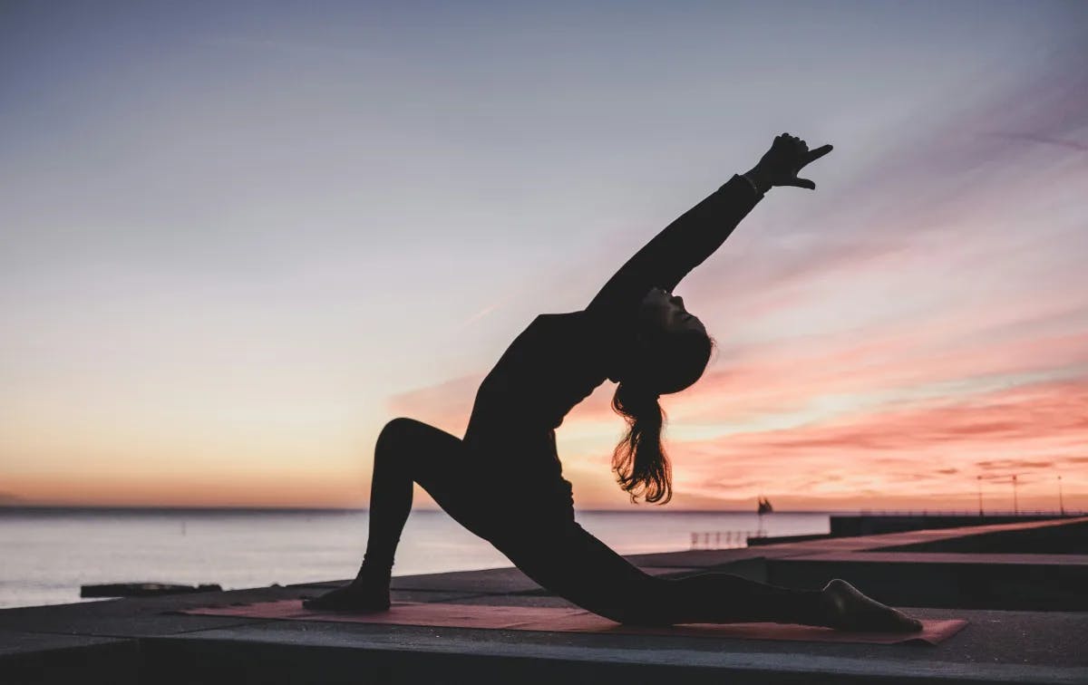 A picture of a woman doing yoga at the sunrise