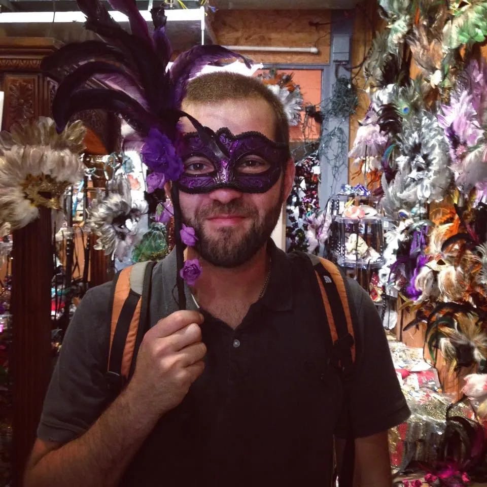 A person holding up a purple masquerade mask in a store