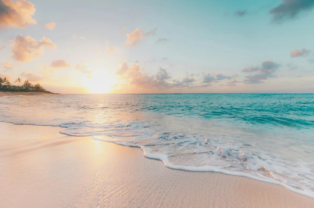 Beach with white sand and turquoise waters at sunrise.