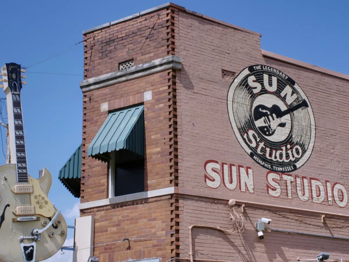 A picture of a concrete building named Sun Studio with a guitar.