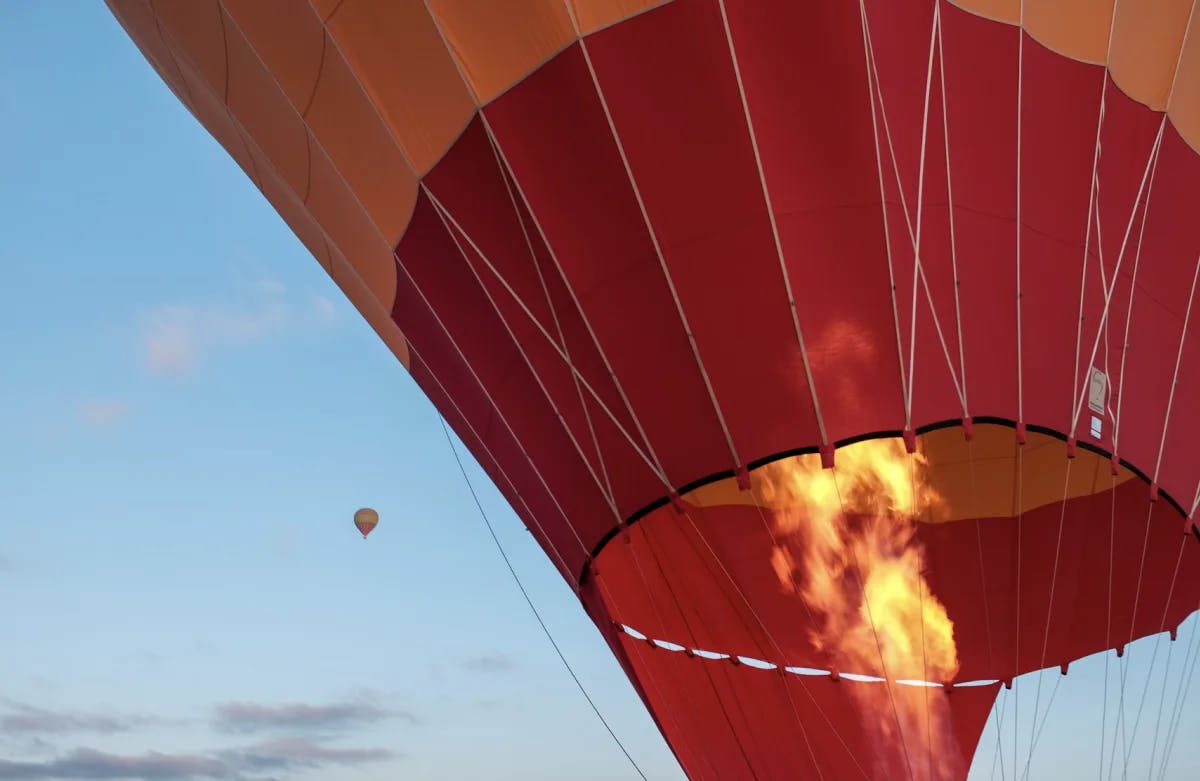 A view of the fire supporting a large hot air balloon with a smaller one in the distance. 