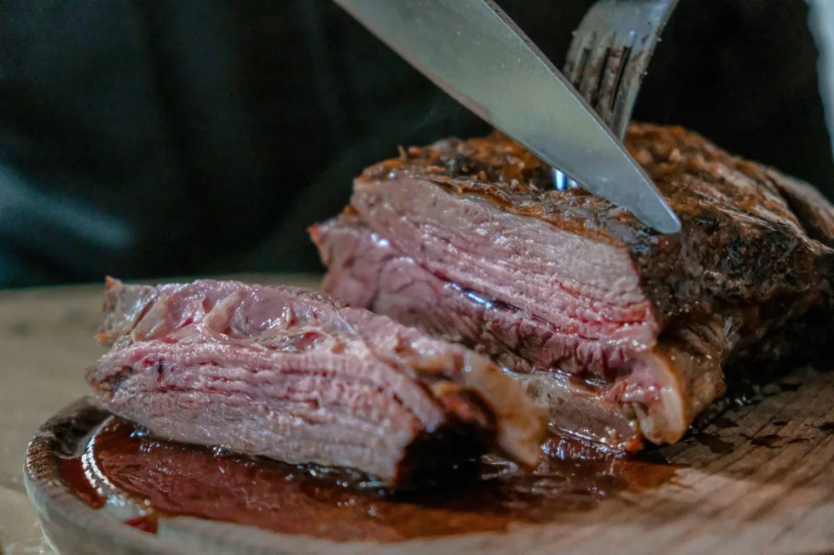 Barbecue meat being sliced on a plate.