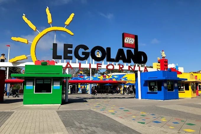 The entrance of Legoland California with a large sign and colorful lego-shaped buildings