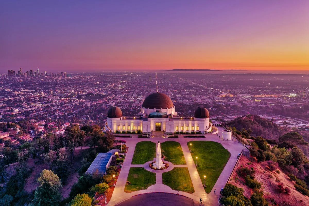 The Griffith Observatory as seen from above at sunset, with the city of LA behind it.
