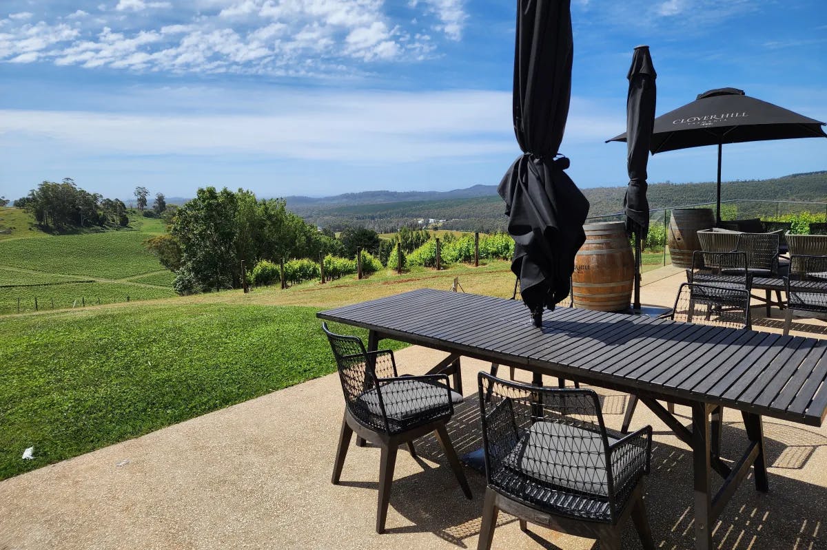 A black outdoor patio table at Clover Hill Winery overlooking rolling green hills on a sunny day.