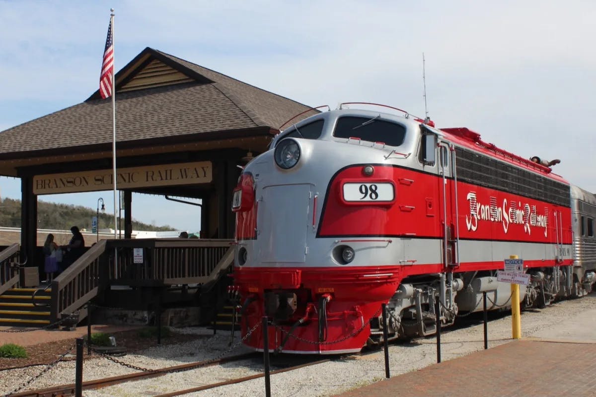 A red vintage passenger train in the station at Branson Scenic Railway.
