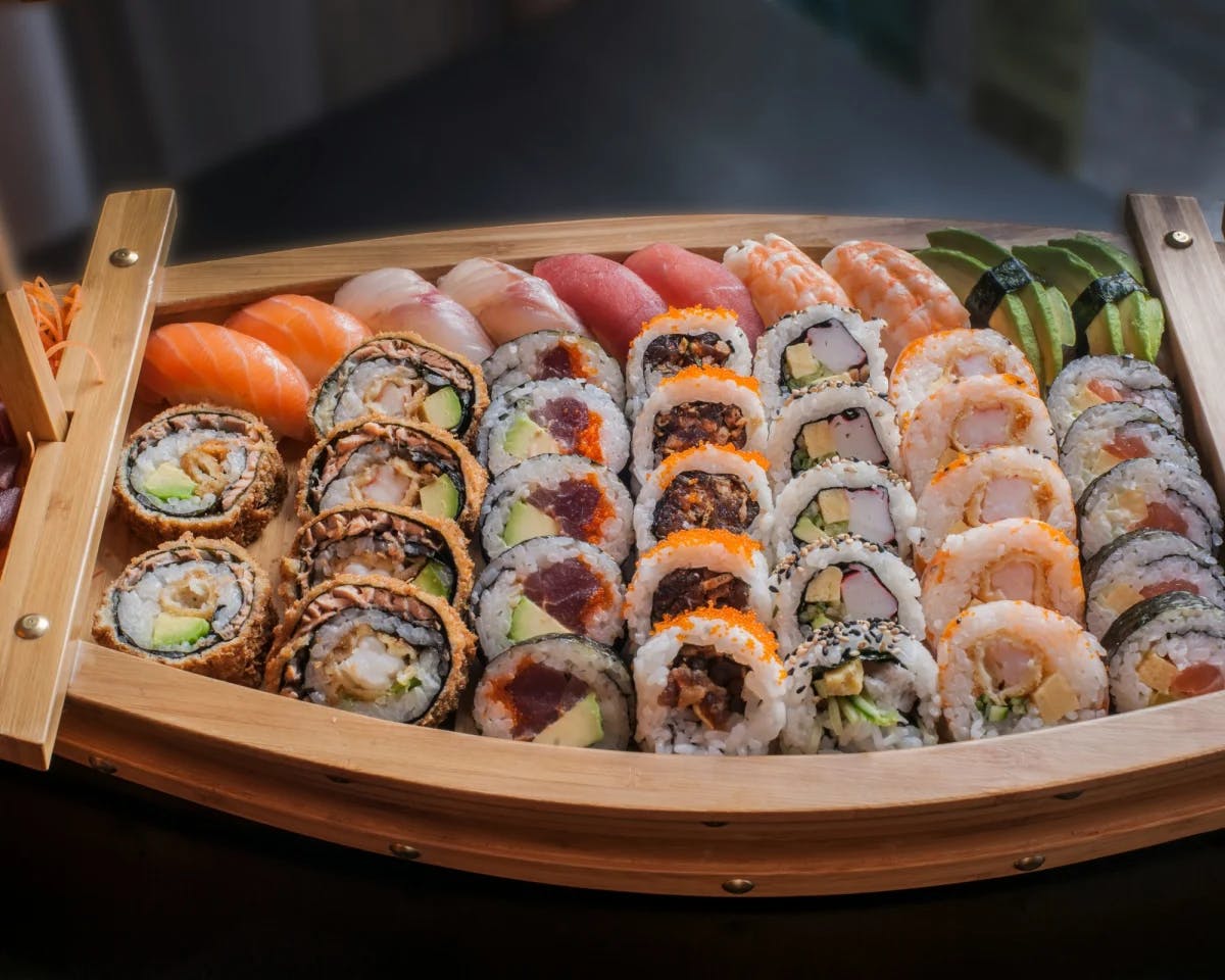 A wooden sushi boat filled with rolls.