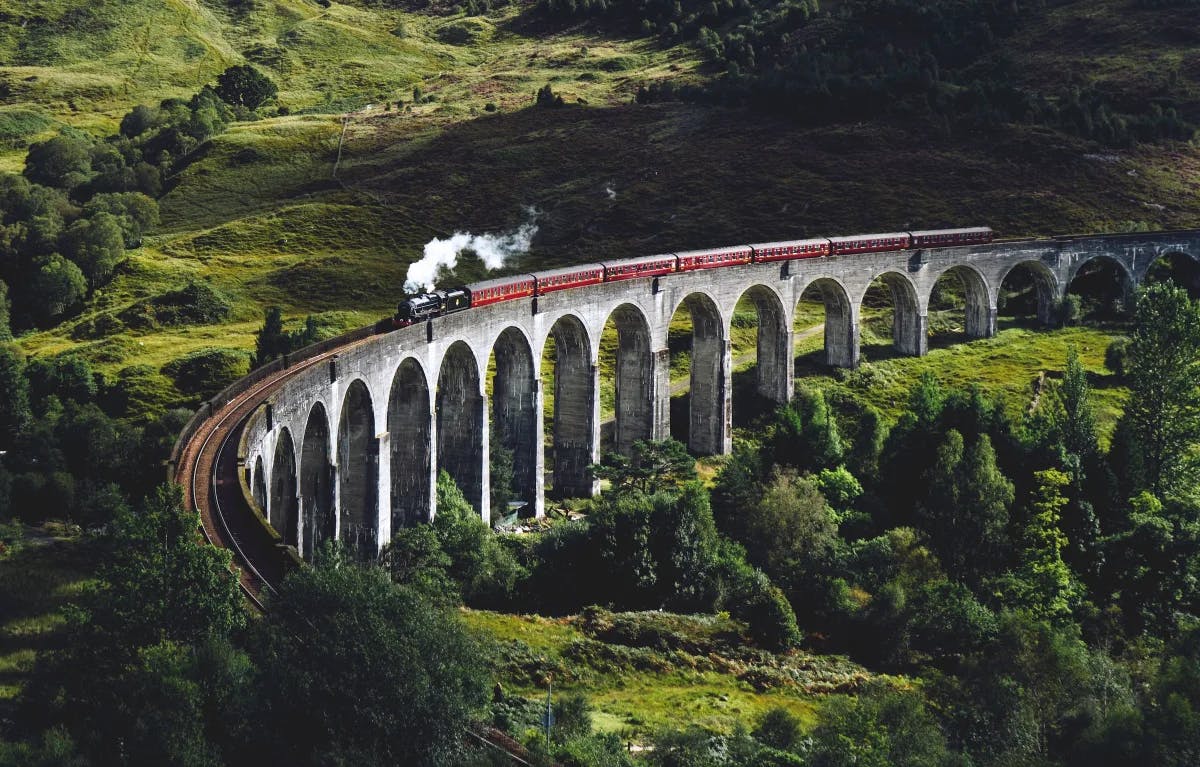Train on bridge surrounded with trees at Glen Finnan Viaduct.